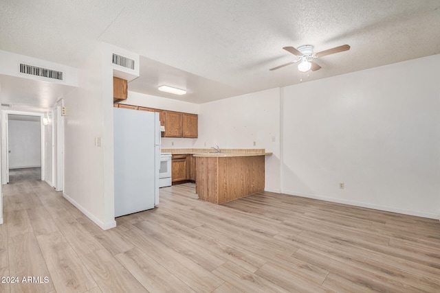 kitchen featuring ceiling fan, kitchen peninsula, a textured ceiling, white appliances, and light wood-type flooring