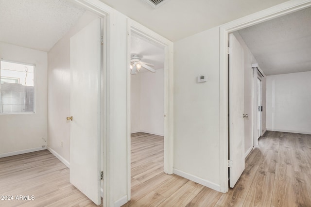 corridor featuring a textured ceiling and light hardwood / wood-style flooring