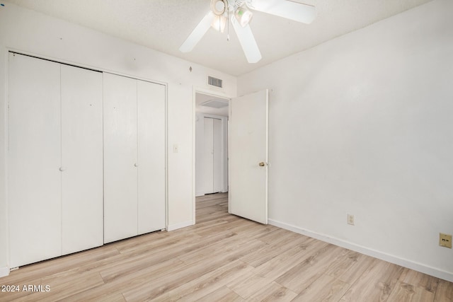 unfurnished bedroom featuring a textured ceiling, light wood-type flooring, a closet, and ceiling fan