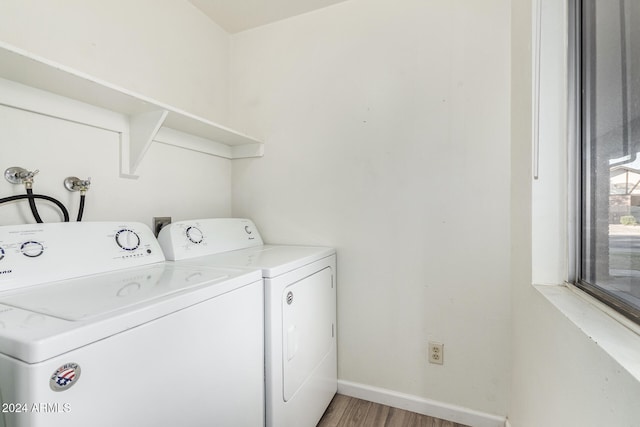 laundry room with washing machine and clothes dryer and hardwood / wood-style floors