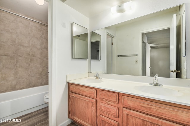 full bathroom with vanity, wood-type flooring, tiled shower / bath combo, and toilet