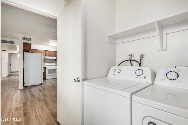 clothes washing area featuring independent washer and dryer, light wood-type flooring, and a textured ceiling