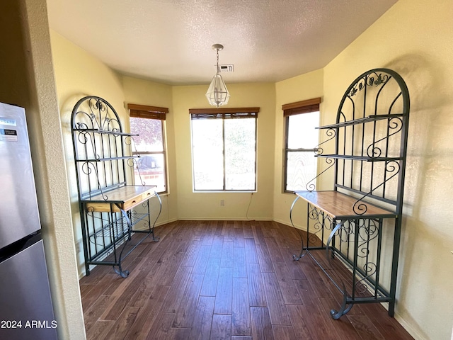 unfurnished dining area featuring dark hardwood / wood-style floors and a textured ceiling