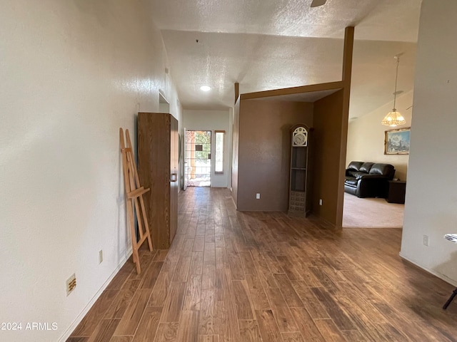 hall with dark hardwood / wood-style floors, a textured ceiling, and lofted ceiling