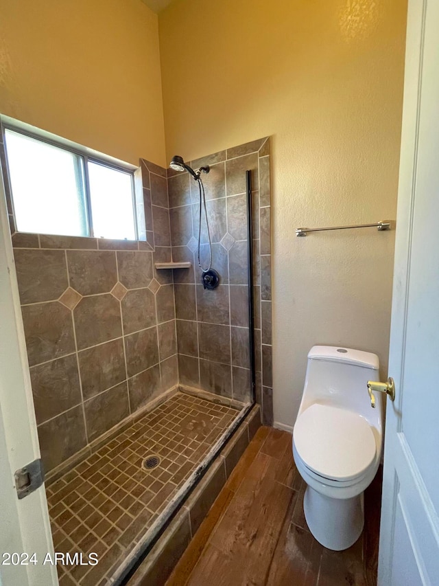 bathroom with toilet, wood-type flooring, and a shower with door