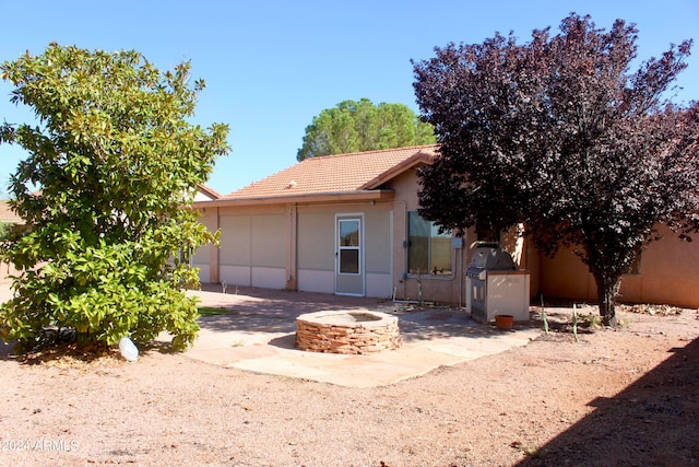 rear view of property featuring a fire pit and a patio