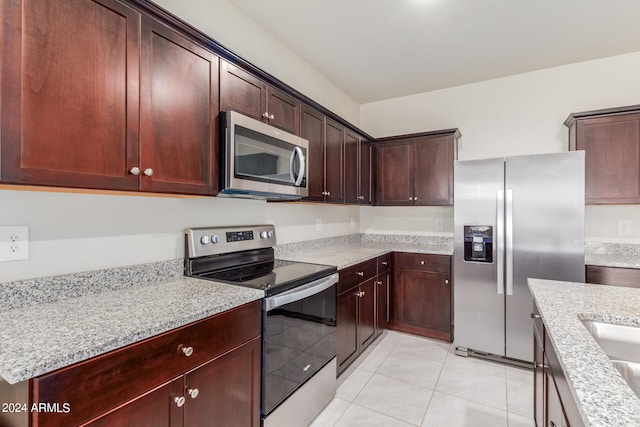 kitchen featuring light stone countertops, stainless steel appliances, and light tile flooring