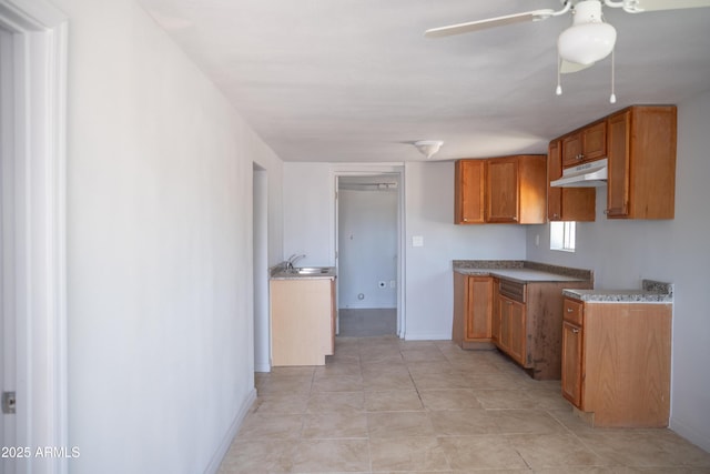 1410 S 24th Ave, Phoenix, AZ 85009 - kitchen with ceiling fan, baseboards, brown cabinetry, and under cabinet range hood