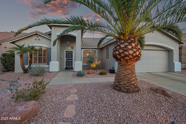 mediterranean / spanish-style house with driveway, a tiled roof, an attached garage, and stucco siding