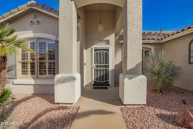 doorway to property with a tiled roof and stucco siding