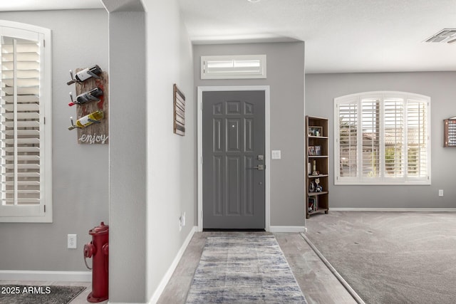 entryway featuring wood finished floors, visible vents, and baseboards