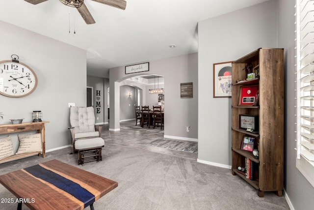 living area with a ceiling fan, arched walkways, baseboards, and carpet