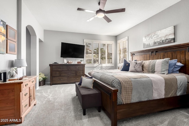 bedroom with arched walkways, a ceiling fan, and light colored carpet