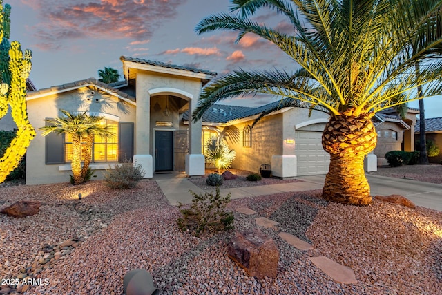 mediterranean / spanish house featuring concrete driveway, an attached garage, and stucco siding