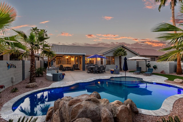 pool at dusk with a patio area, a fenced backyard, a fenced in pool, and outdoor dining space