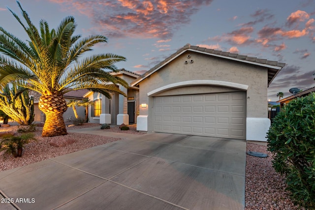 mediterranean / spanish house with concrete driveway, an attached garage, and stucco siding