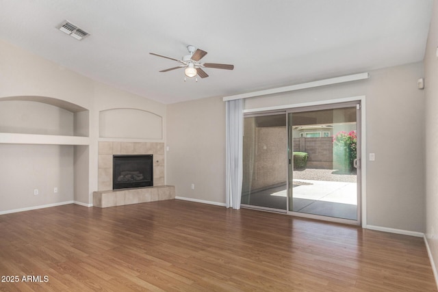 2191 W Goldmine Mountain Dr, Queen Creek, AZ 85144 - unfurnished living room with ceiling fan, wood finished floors, a tile fireplace, and baseboards