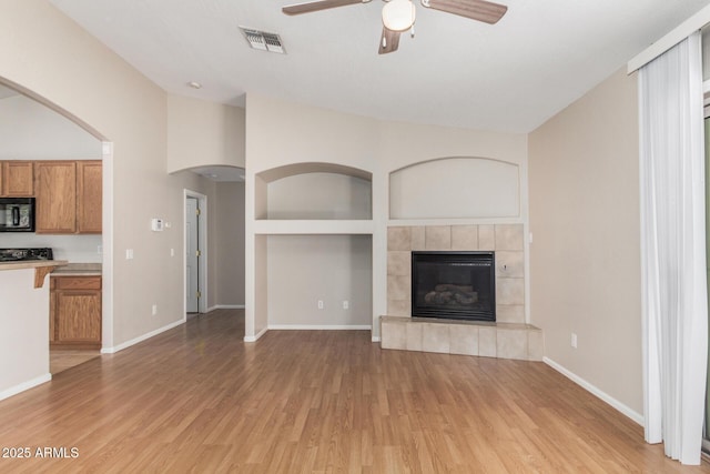 2191 W Goldmine Mountain Dr, Queen Creek, AZ 85144 - unfurnished living room with ceiling fan, light wood-type flooring, a fireplace, and baseboards