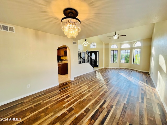 unfurnished living room featuring ceiling fan with notable chandelier and hardwood / wood-style flooring