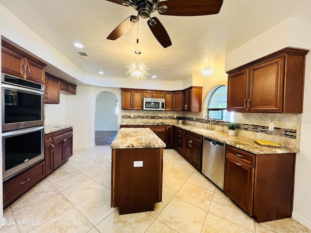 kitchen featuring appliances with stainless steel finishes, a kitchen island, pendant lighting, and light stone counters