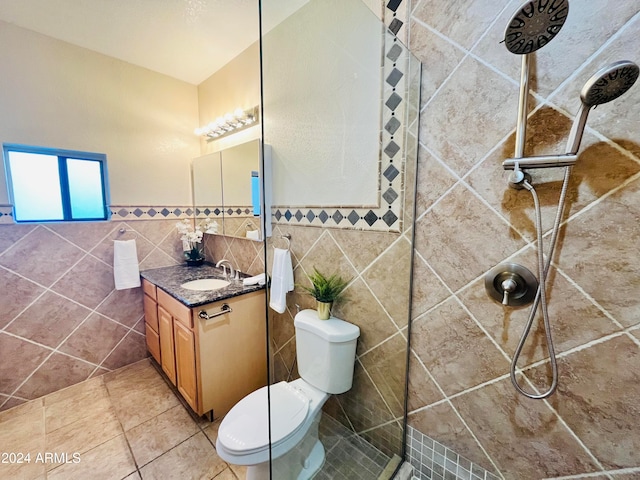 bathroom featuring a tile shower, vanity, tile walls, tile patterned flooring, and toilet