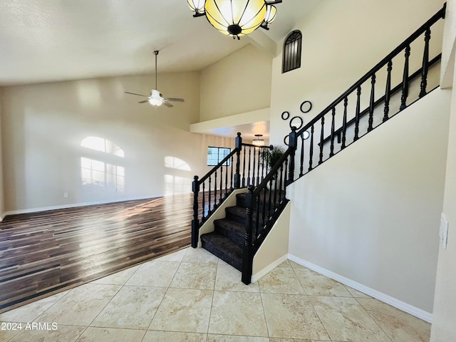 staircase featuring hardwood / wood-style floors, ceiling fan, and high vaulted ceiling