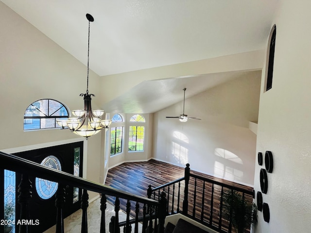 stairs featuring wood-type flooring, ceiling fan with notable chandelier, and high vaulted ceiling