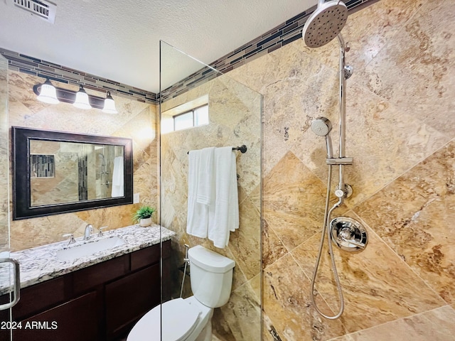 bathroom featuring vanity, toilet, tiled shower, and a textured ceiling