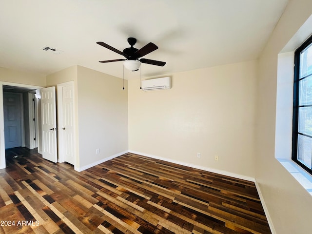 spare room featuring dark hardwood / wood-style floors, an AC wall unit, and ceiling fan