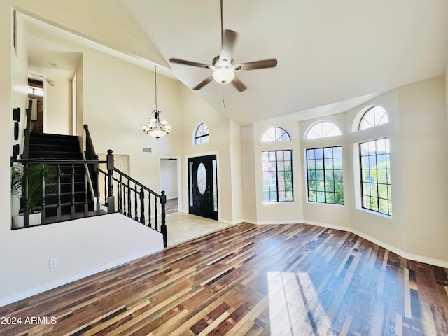 entryway featuring ceiling fan with notable chandelier, wood-type flooring, and high vaulted ceiling