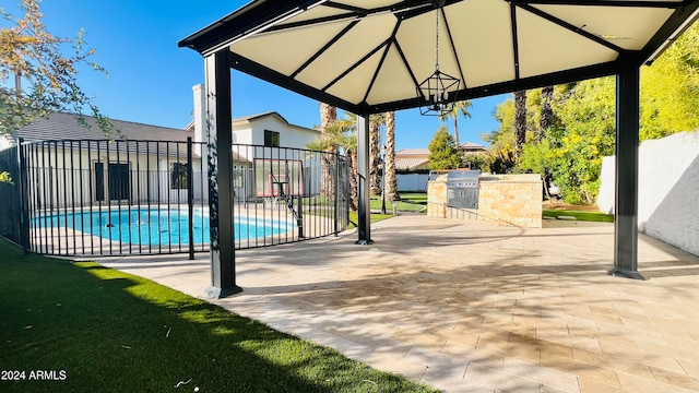 view of patio featuring a gazebo, an outdoor kitchen, and a fenced in pool