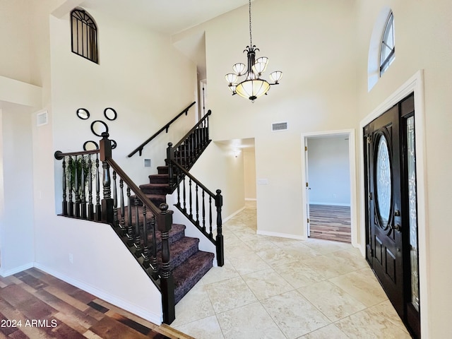 foyer with a chandelier, light wood-type flooring, and a towering ceiling