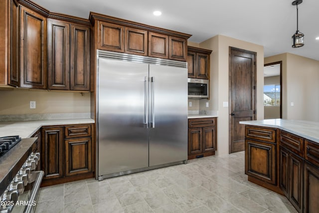 kitchen with dark brown cabinets, decorative light fixtures, and high end appliances