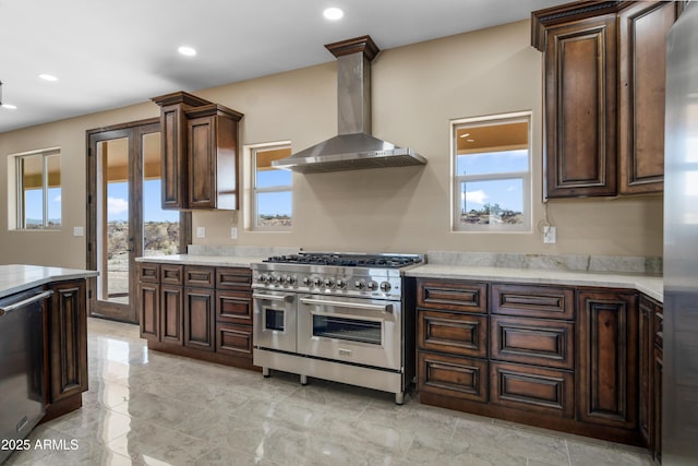 kitchen with appliances with stainless steel finishes, ornate columns, plenty of natural light, and wall chimney exhaust hood