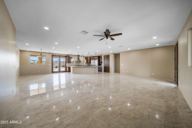 unfurnished living room featuring ceiling fan with notable chandelier