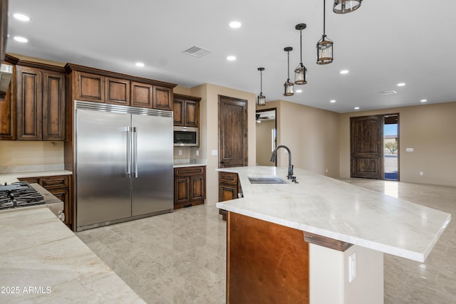 kitchen featuring ceiling fan, sink, stainless steel appliances, light stone counters, and decorative light fixtures