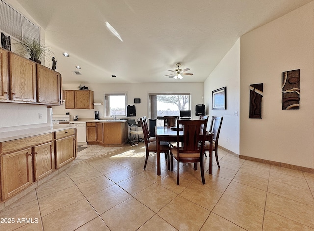 tiled dining space with ceiling fan, lofted ceiling, and sink