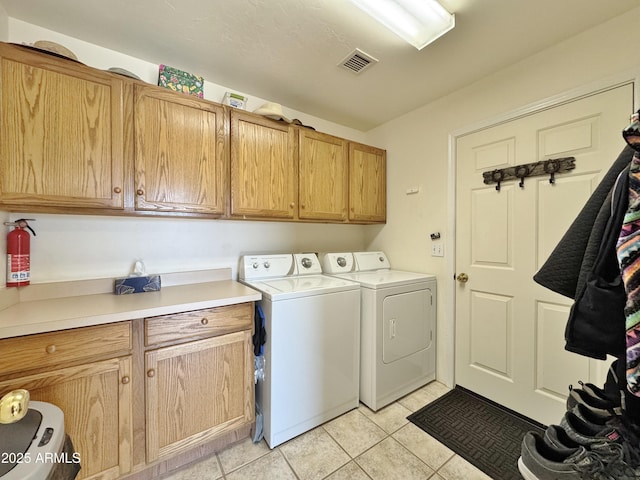 washroom with cabinets, washing machine and dryer, and light tile patterned floors