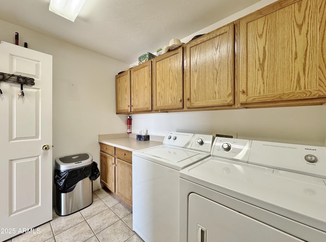 laundry room featuring washer and dryer, light tile patterned floors, and cabinets