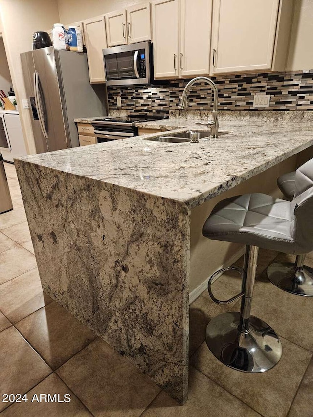 kitchen featuring appliances with stainless steel finishes, tasteful backsplash, light stone counters, and light tile flooring