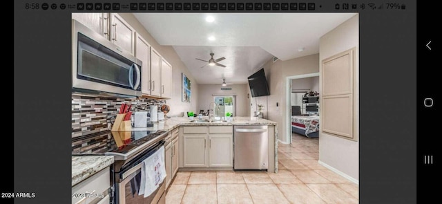 kitchen featuring appliances with stainless steel finishes, tasteful backsplash, light tile floors, light stone countertops, and ceiling fan