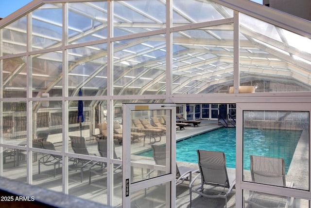 pool featuring glass enclosure and a patio area