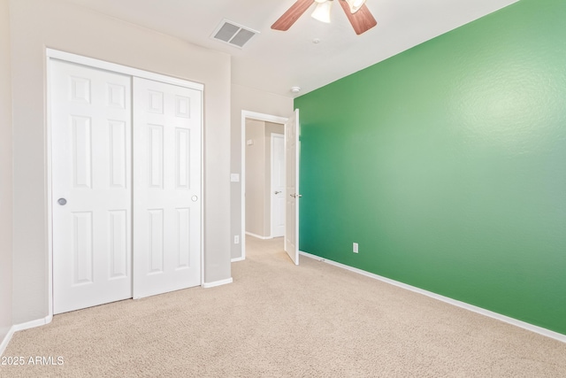 unfurnished bedroom featuring light colored carpet, a closet, and ceiling fan