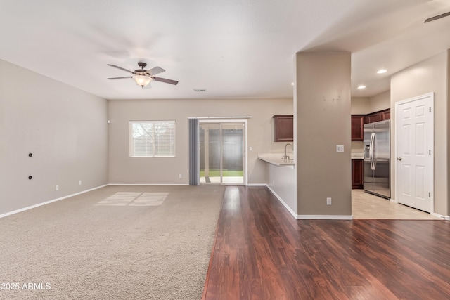 unfurnished living room with wood-type flooring, sink, and ceiling fan