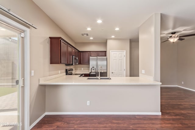 kitchen featuring stainless steel appliances, dark hardwood / wood-style flooring, kitchen peninsula, and sink