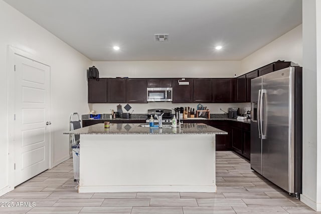 kitchen featuring stainless steel appliances, sink, a kitchen island with sink, and dark brown cabinets