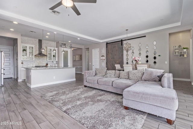 12083 W Peak View Rd, Peoria, AZ 85383 - living area with a barn door, a tray ceiling, ceiling fan, baseboards, and recessed lighting
