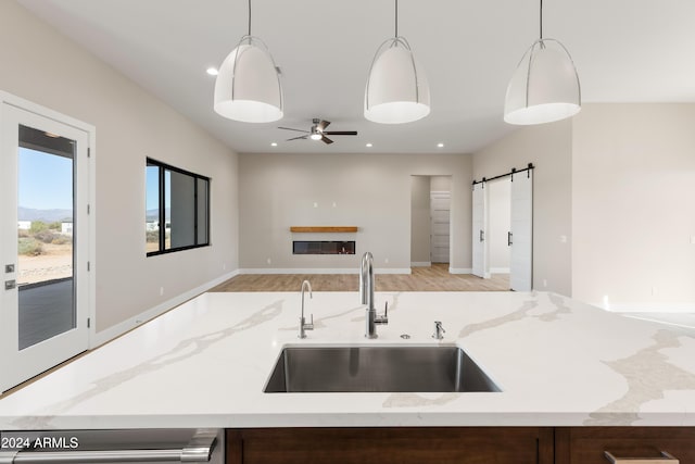 kitchen featuring a barn door, sink, light wood-type flooring, and pendant lighting