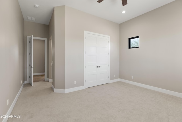 unfurnished bedroom with light colored carpet, a closet, and ceiling fan