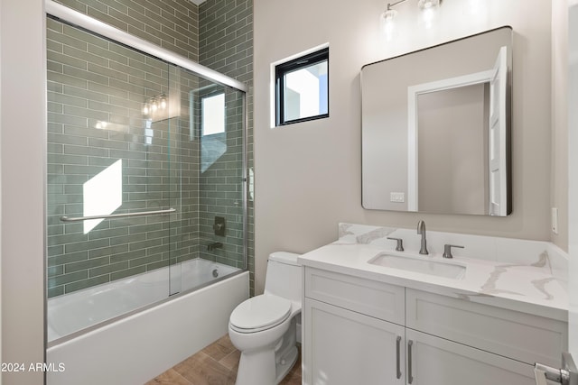 full bathroom featuring vanity, toilet, hardwood / wood-style flooring, and shower / bath combination with glass door